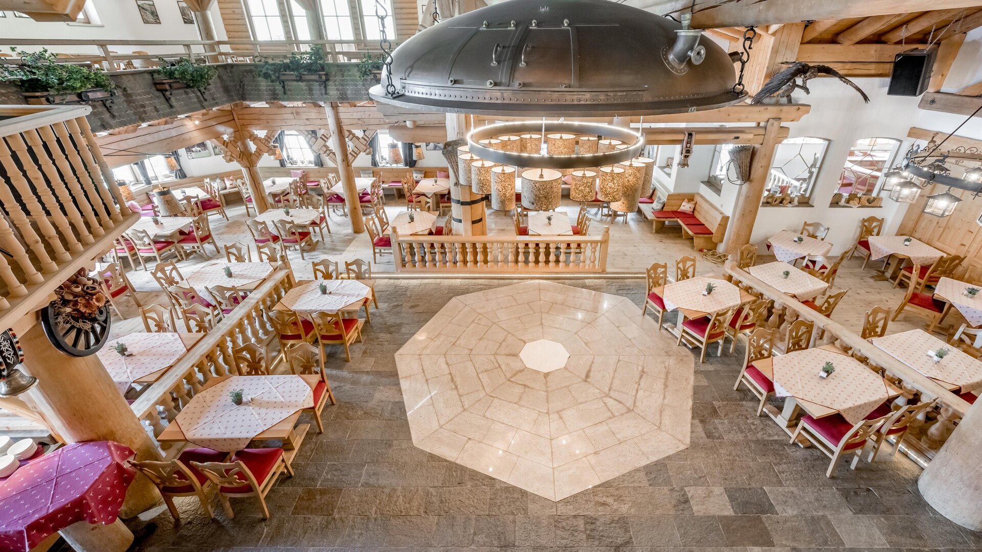 Ein gemütliches Restaurant mit stilvoller Holzverkleidung und angrenzenden Essbereichen. Die Tische sind liebevoll gedeckt und das Lichtkonzept schafft eine einladende Atmosphäre.