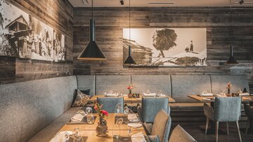 Ein gemütliches Restaurant mit Holzwänden und stilvollen Möbeln. Auf den Tischen sind Besteck und Blumendekorationen arrangiert.