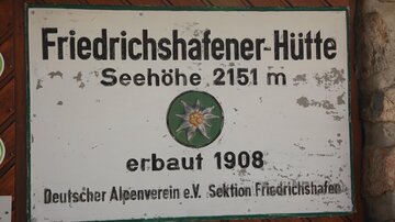 Ein Schild der Friedrichshafener Hütte in einer Höhe von 2151 m. Es wurde 1908 erbaut und gehört zum Deutschen Alpenverein.