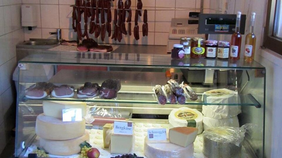 Ein Kühlschrank mit verschiedenen Käsearten, Wurstwaren und einigen Flaschen. Die Auswahl wirkt frisch und einladend.