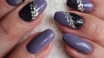 Beautiful fingernails in purple and black with glitter accents. The nail art is designed elegantly and trendily.