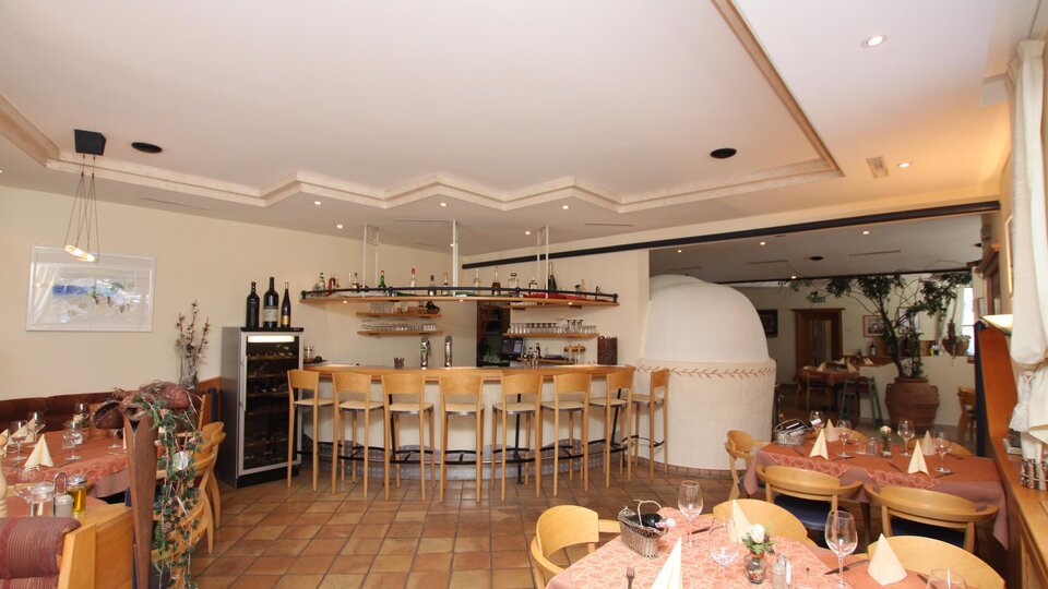 Ein gemütliches Restaurant mit einer Bar und Holzmöbeln. Die Tische sind elegant gedeckt und es befindet sich ein schöner Innenbereich.