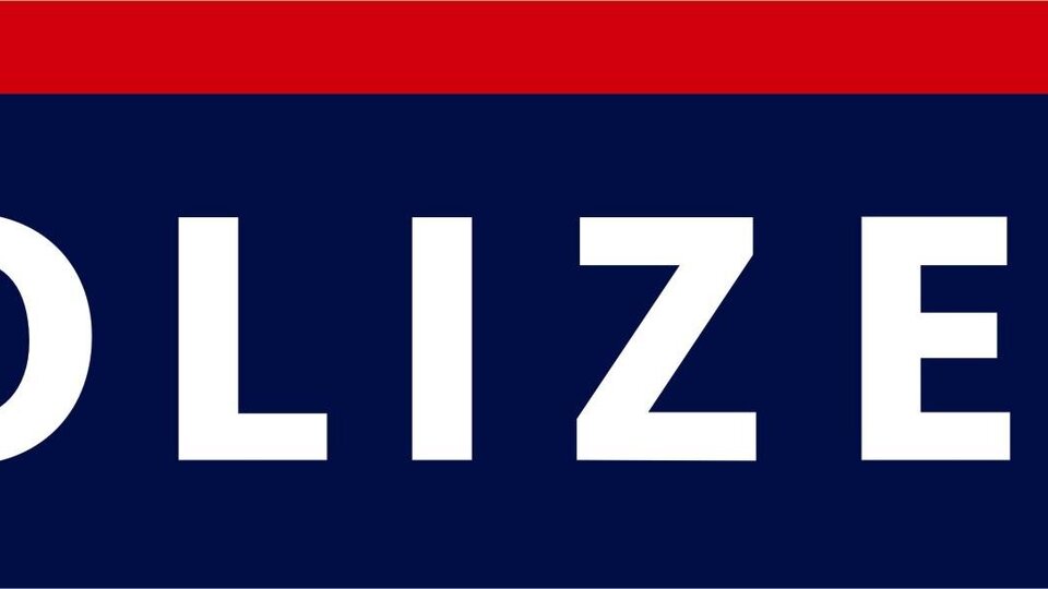 Ein Schild der Polizei mit dem Wort "POLIZEI" in großen, weißen Buchstaben. Darunter ist ein Wappen abgebildet.