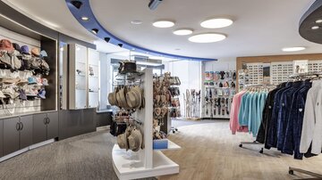 Ein moderner Einzelhandelsraum mit verschiedenen Accessoires, einschließlich Hüte und Bekleidung. Die Wände sind hell und freundlich gestaltet, was eine einladende Atmosphäre schafft.